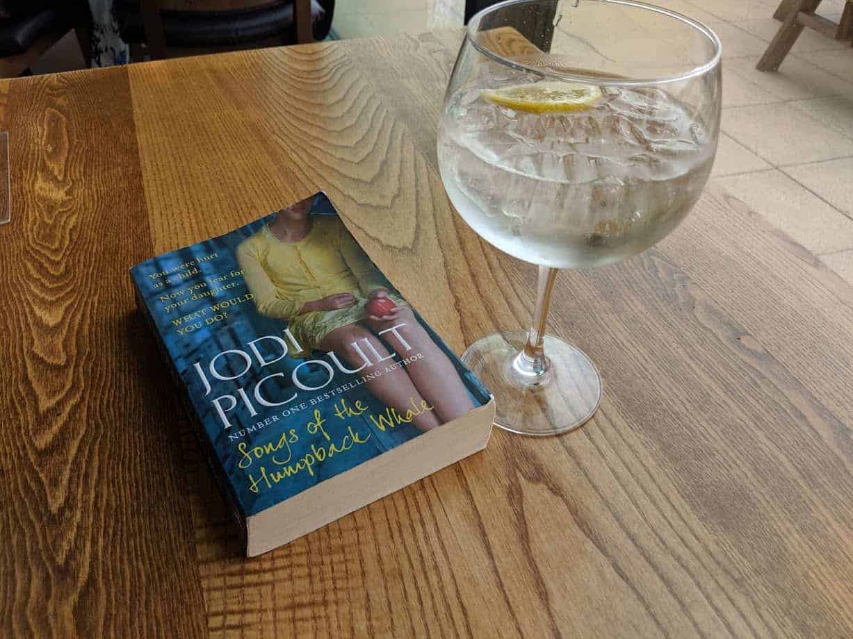 a book on a table with a glass of gin