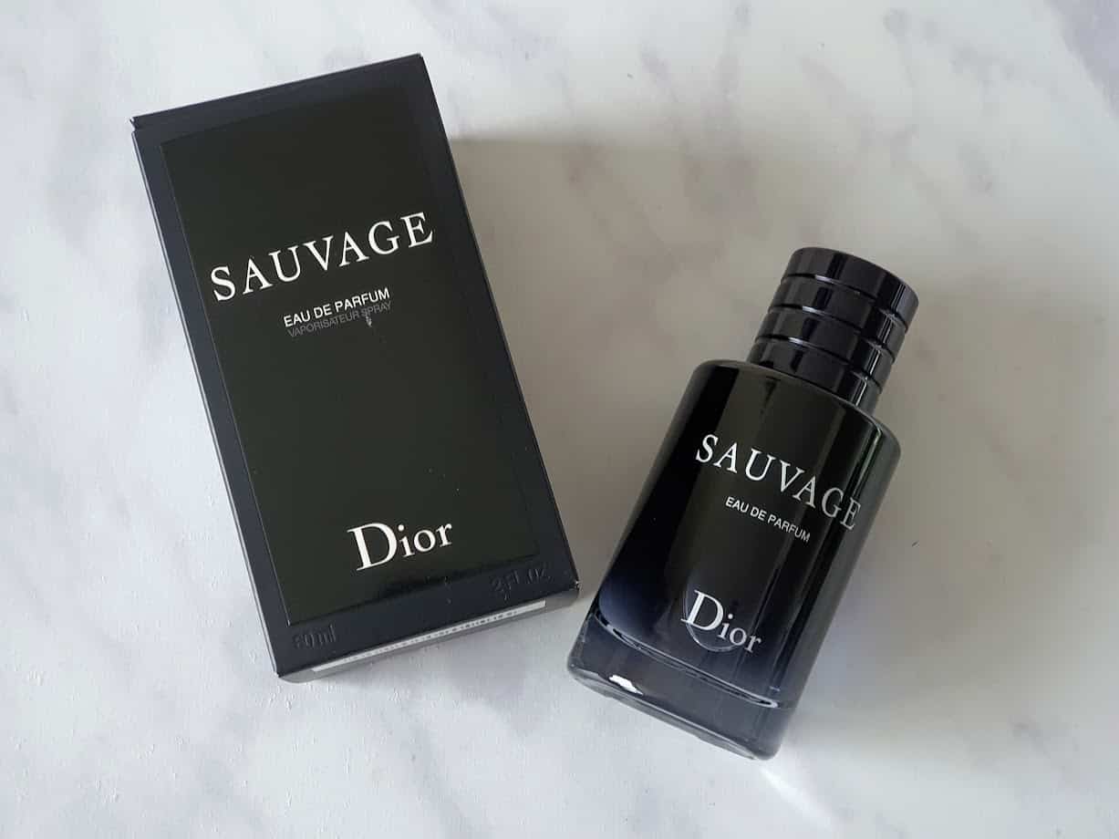 Black bottle of Sauvage by Dior with black cardboard packaging on marble background
