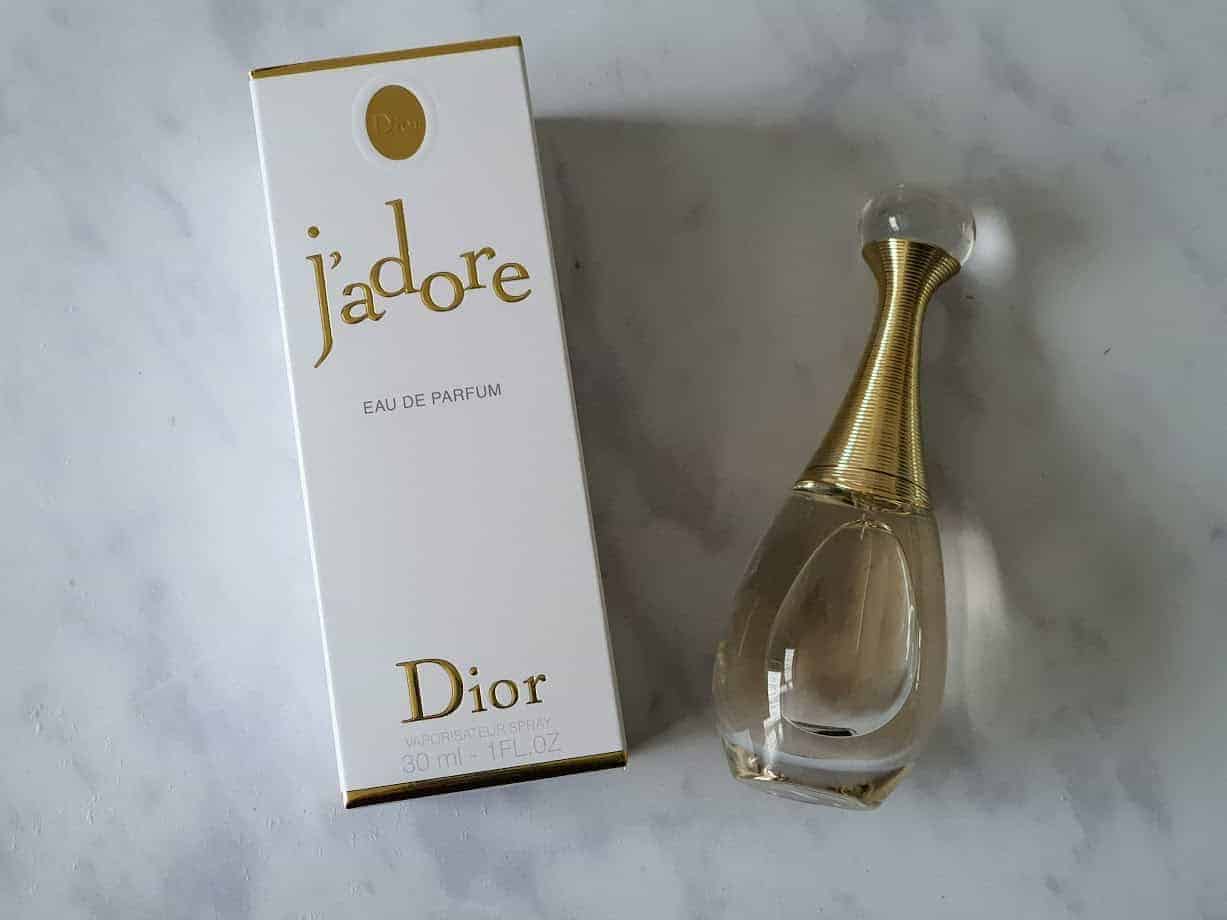 Bottle of J\'Adore by Dior plus white box on marble background