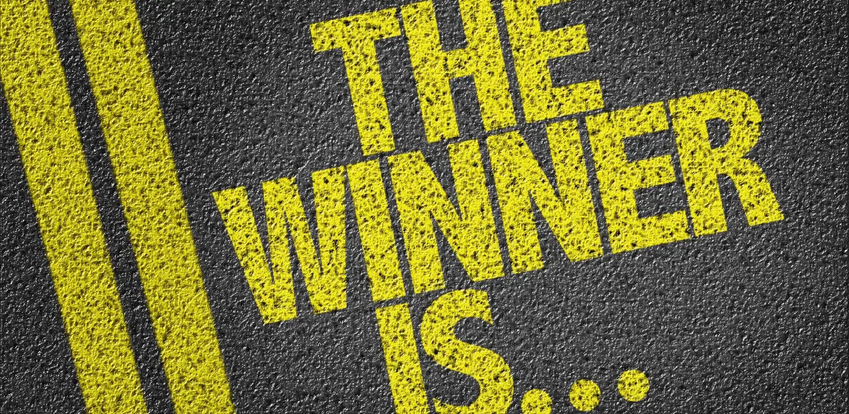 A paved road with double yellow lines, next to the words "The Winner Is..."
