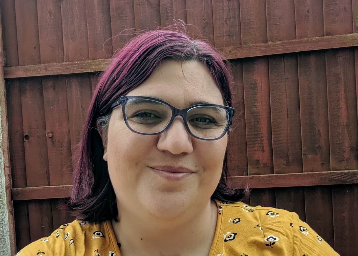 Jen wearing glasses outside in front of brown fence