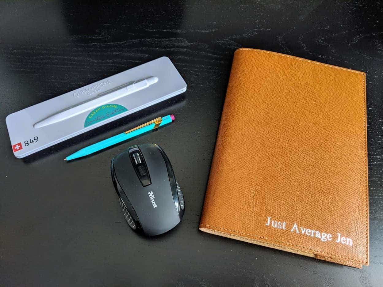 An orange notebook, pen and black mouse
