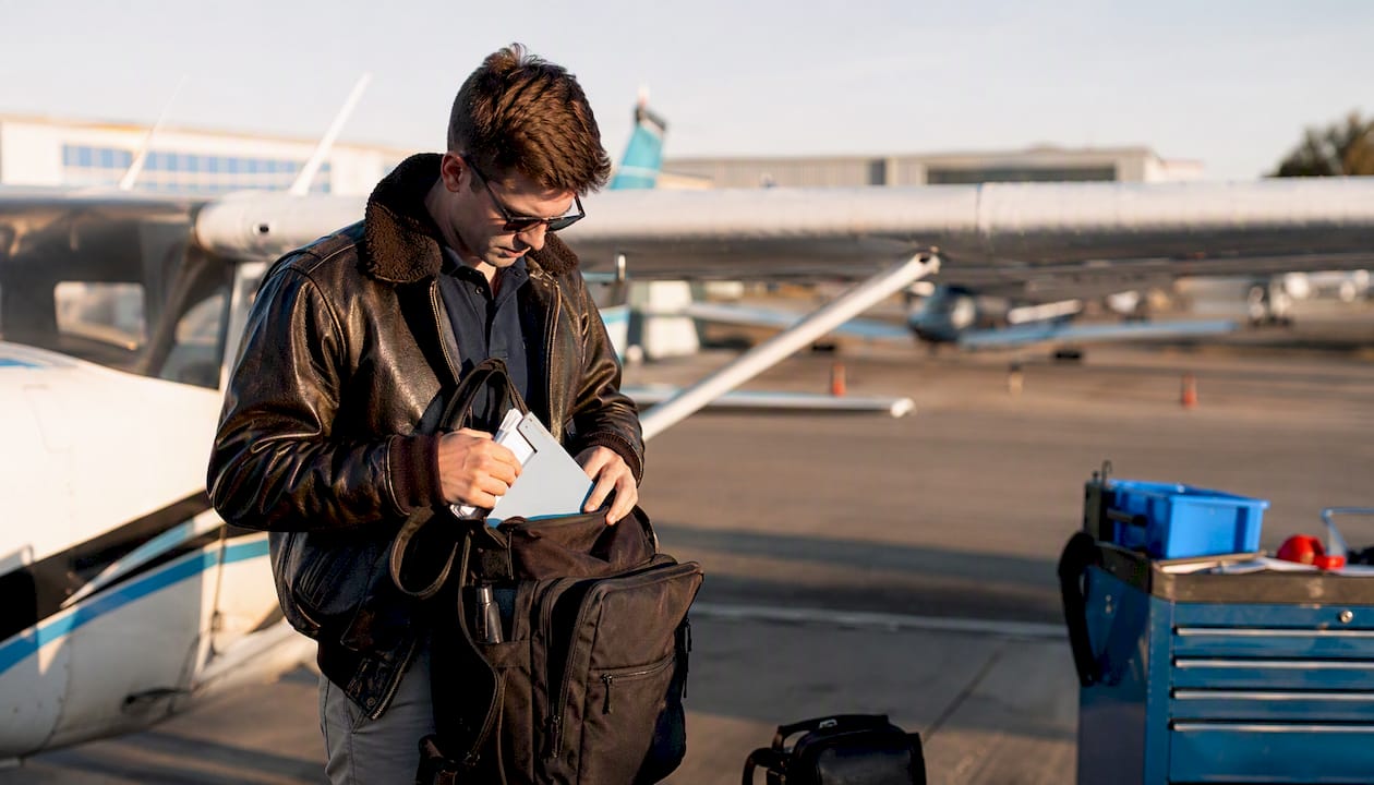 Pilot preparing flight gear near airplane