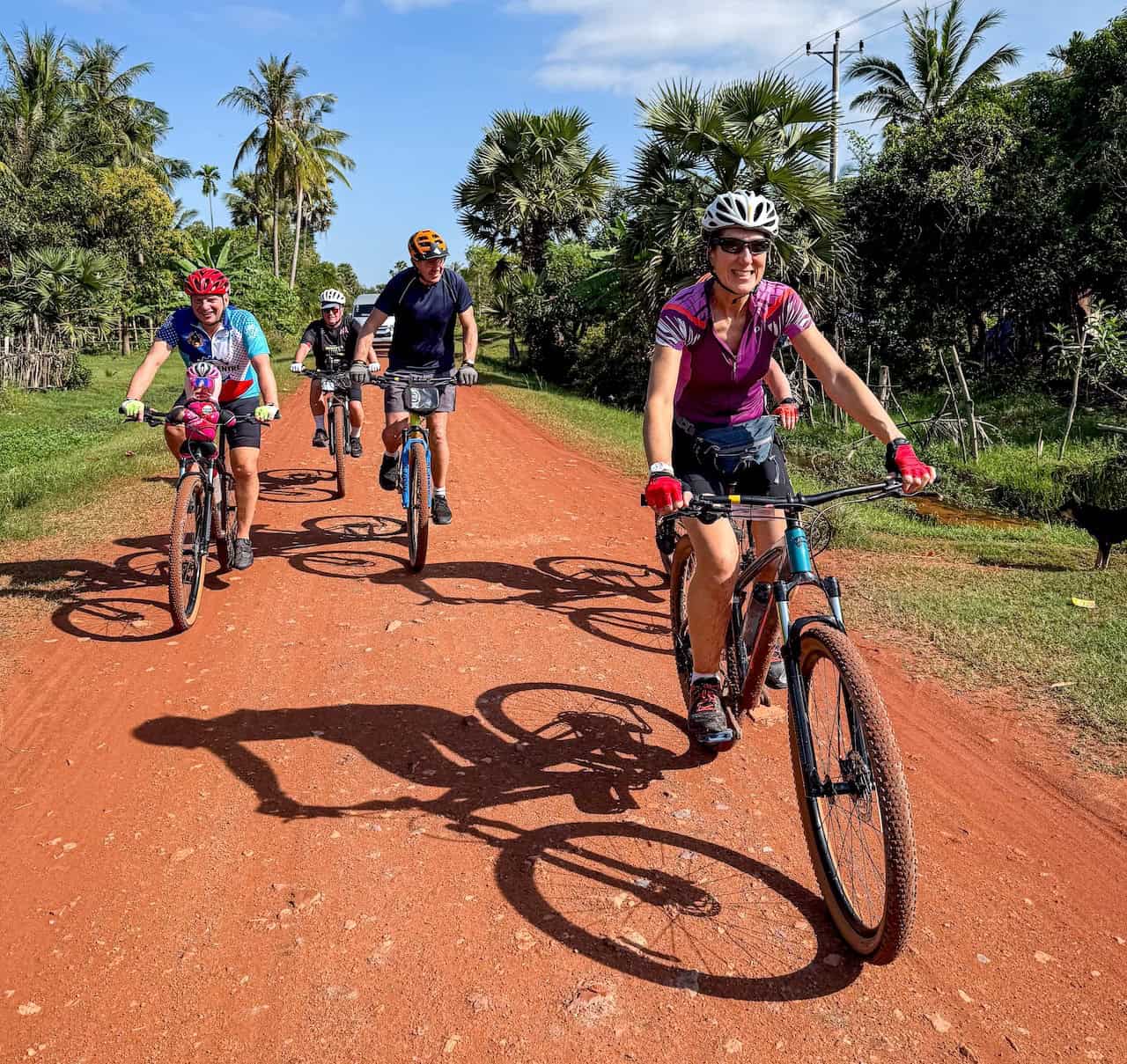 Cyclists riding from Phnom Penh to Siem Reap through quiet countryside roads, rice paddies, Khmer villages, sugar palm trees, and scenic backroads.