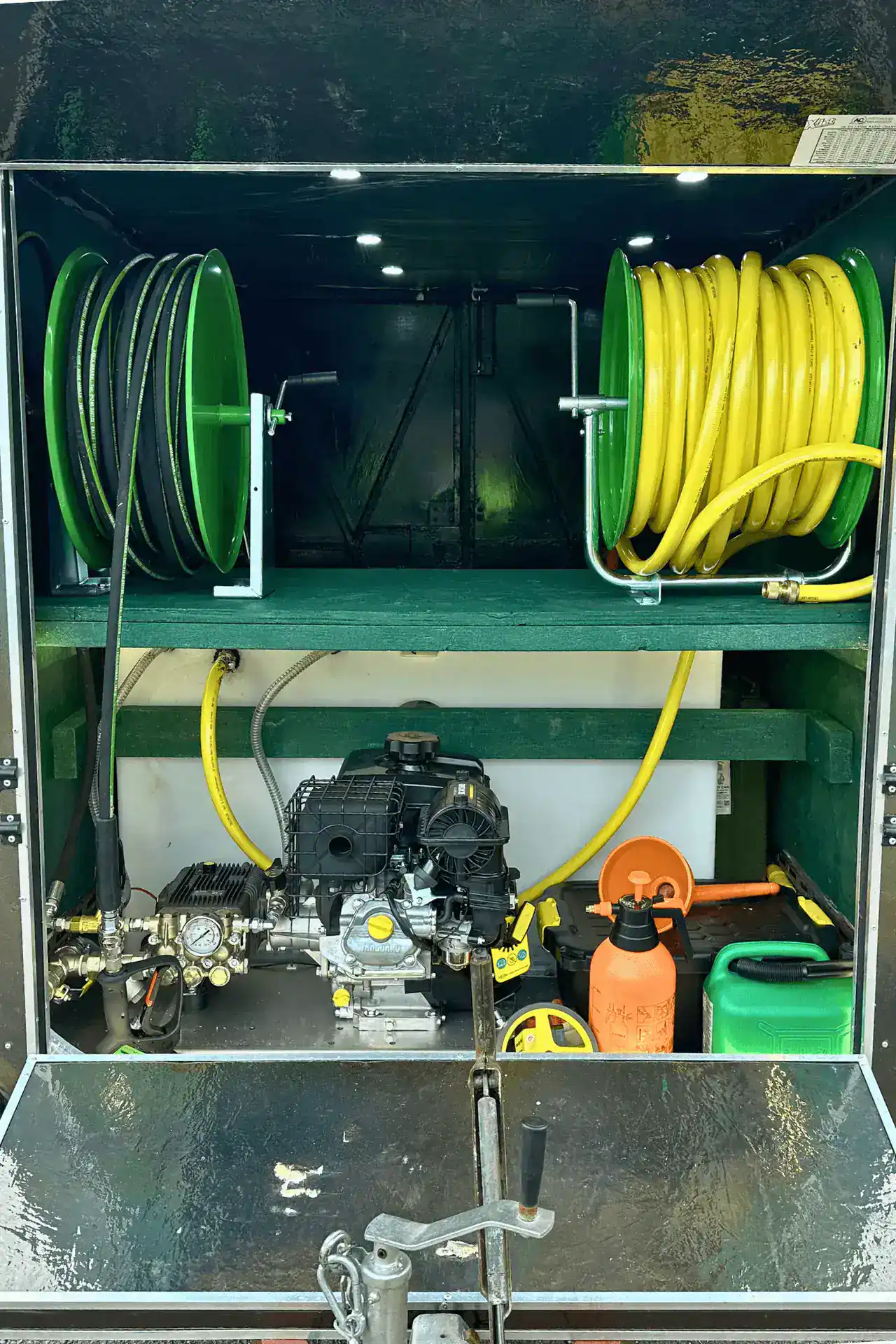 Pressure washer hoses and tools organised in a green and yellow reel.
