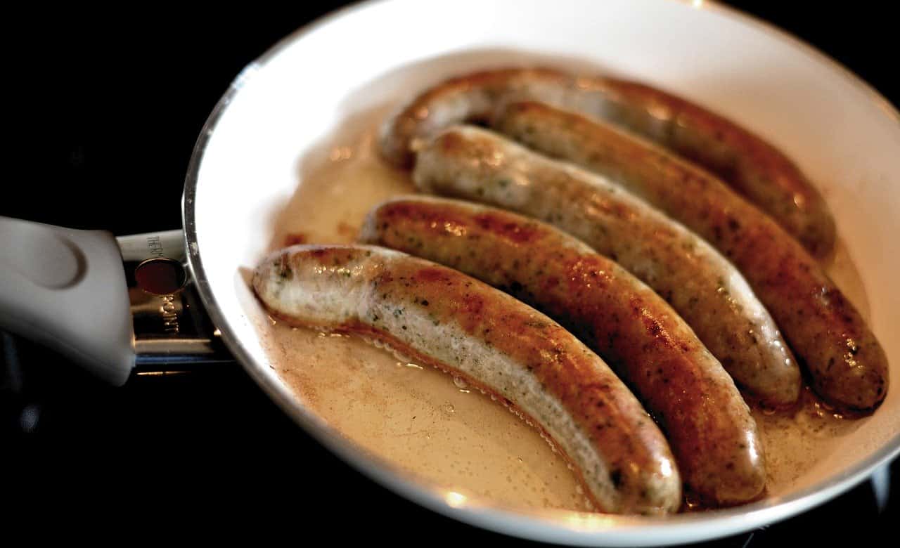 Kielbasa frying in a pan.