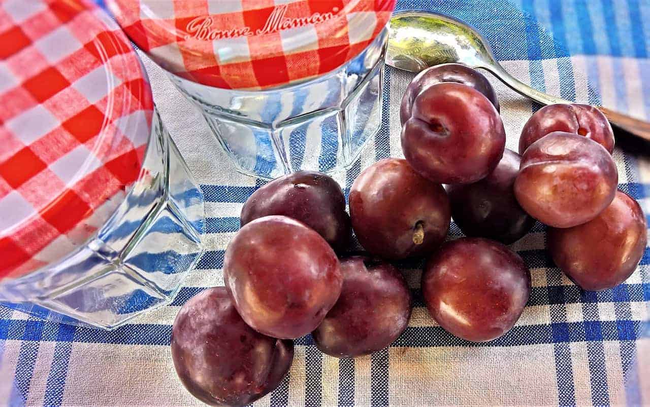 Plums next to mason jars.