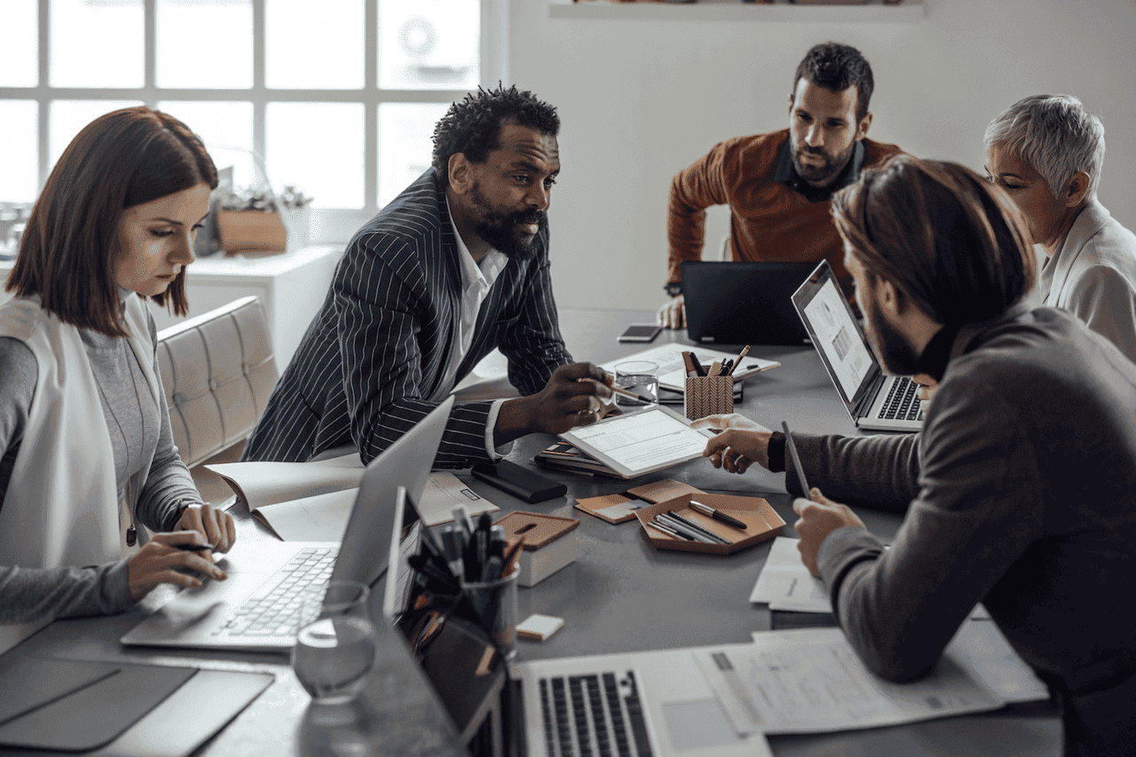 Focused business team collaborating around a table in a modern office to achieve outcome-driven results for strategic success.