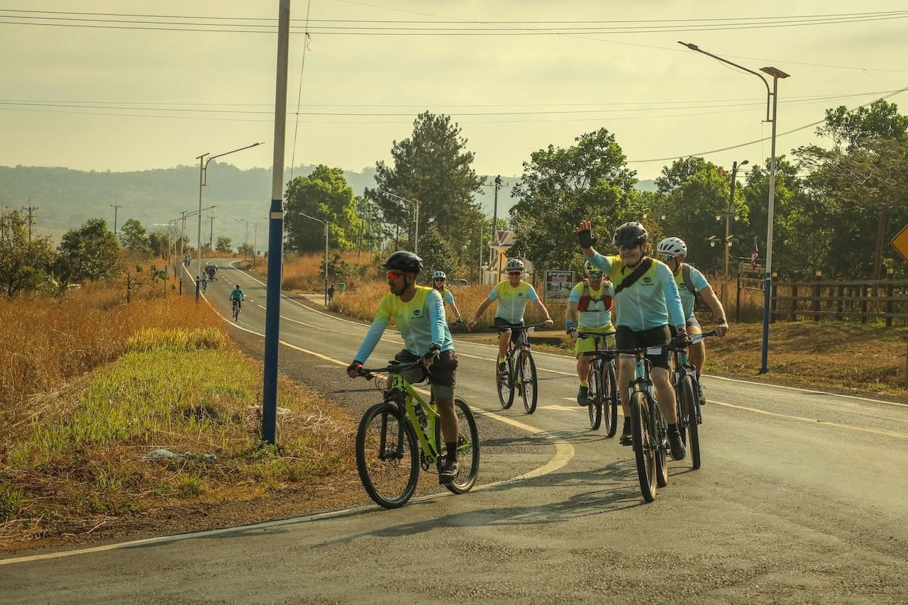 Cyclists riding from Angkor Wat toward Bangkok through authentic countryside landscapes, traditional villages, rice fields, and scenic backroads in Cambodia and Thailand.