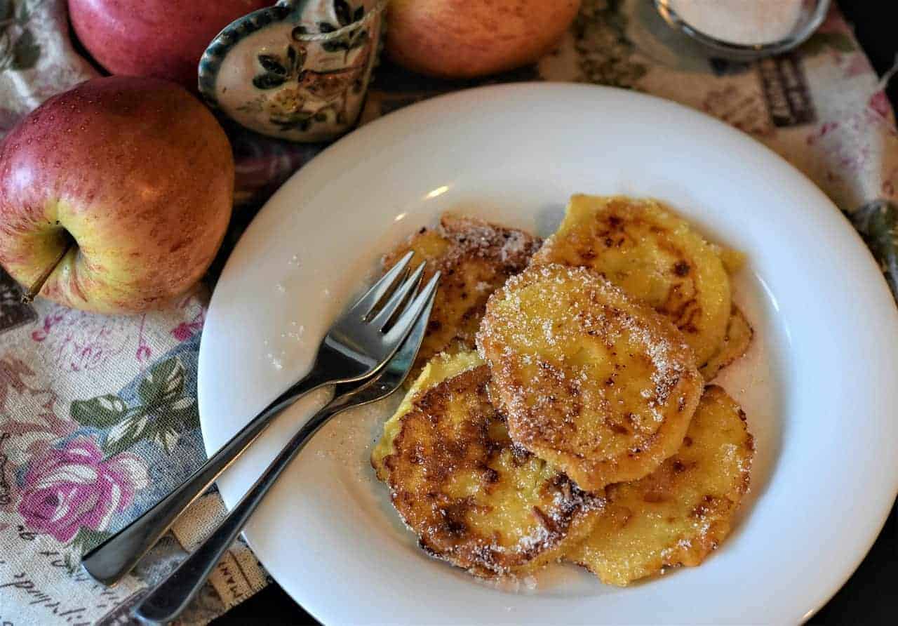 Delicious racuchy pancakes in a plate next to apples.