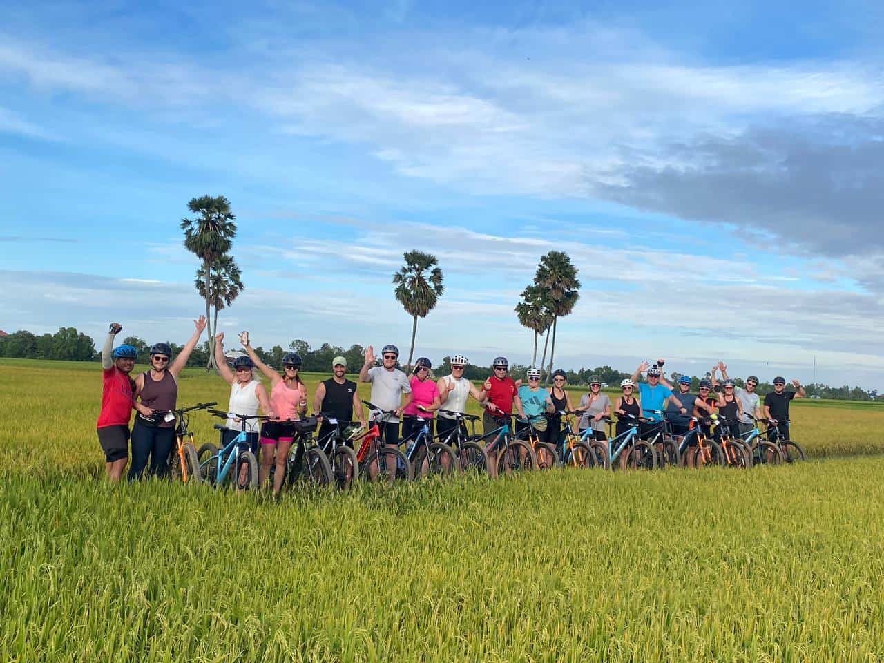 Cambodia Cycling Tours: Cyclists riding along quiet backroads in rural Cambodia, passing traditional villages, rice fields, and scenic countryside landscapes on a Southeast Asia cycling expedition.