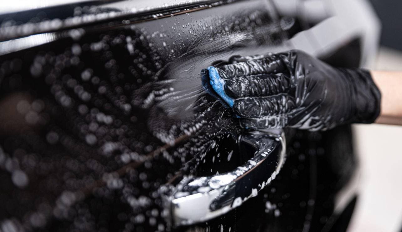 Clay bar decontamination on black car paint during auto detailing