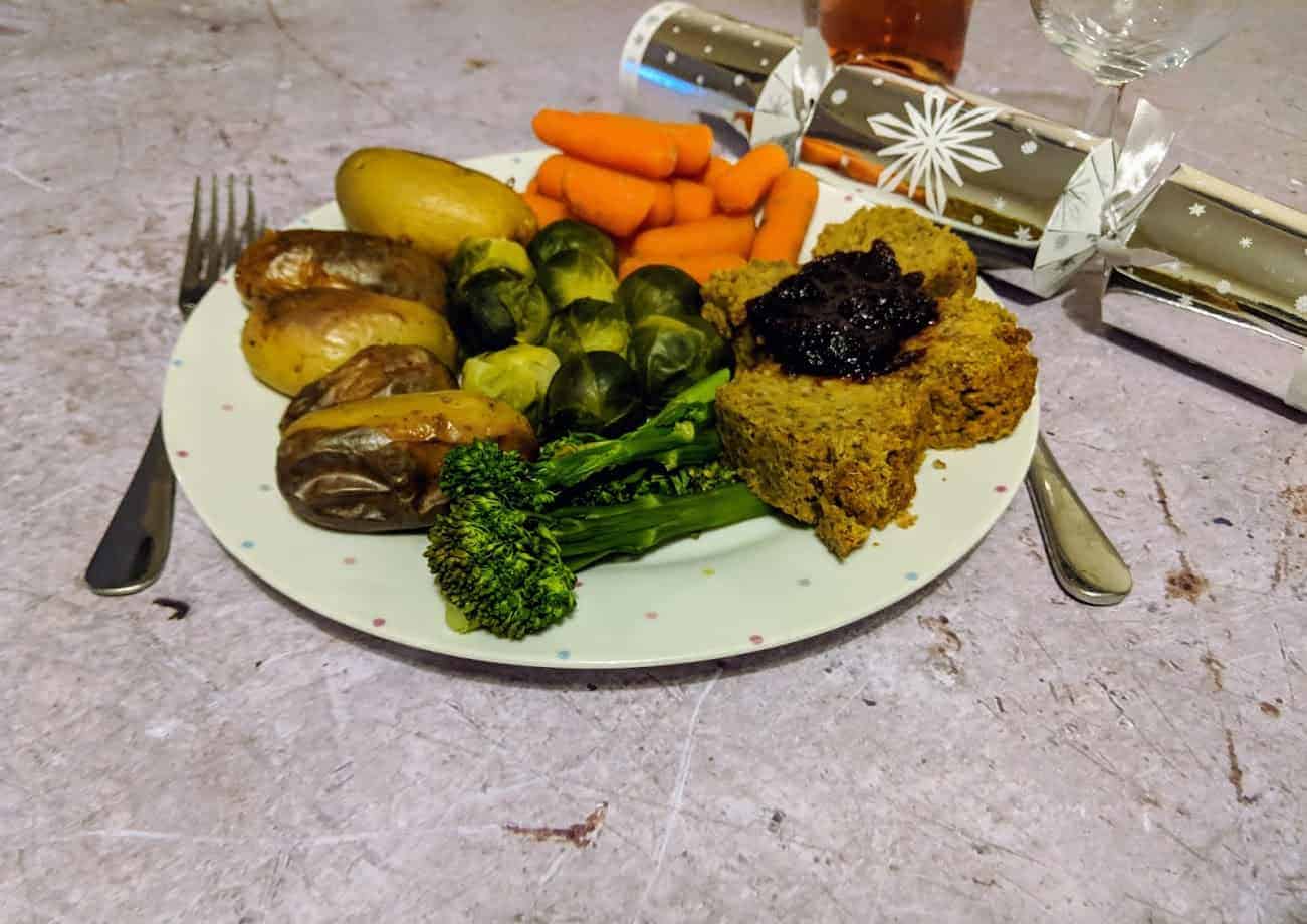 White plate with Christmas dinner and a silver Christmas cracker to the side