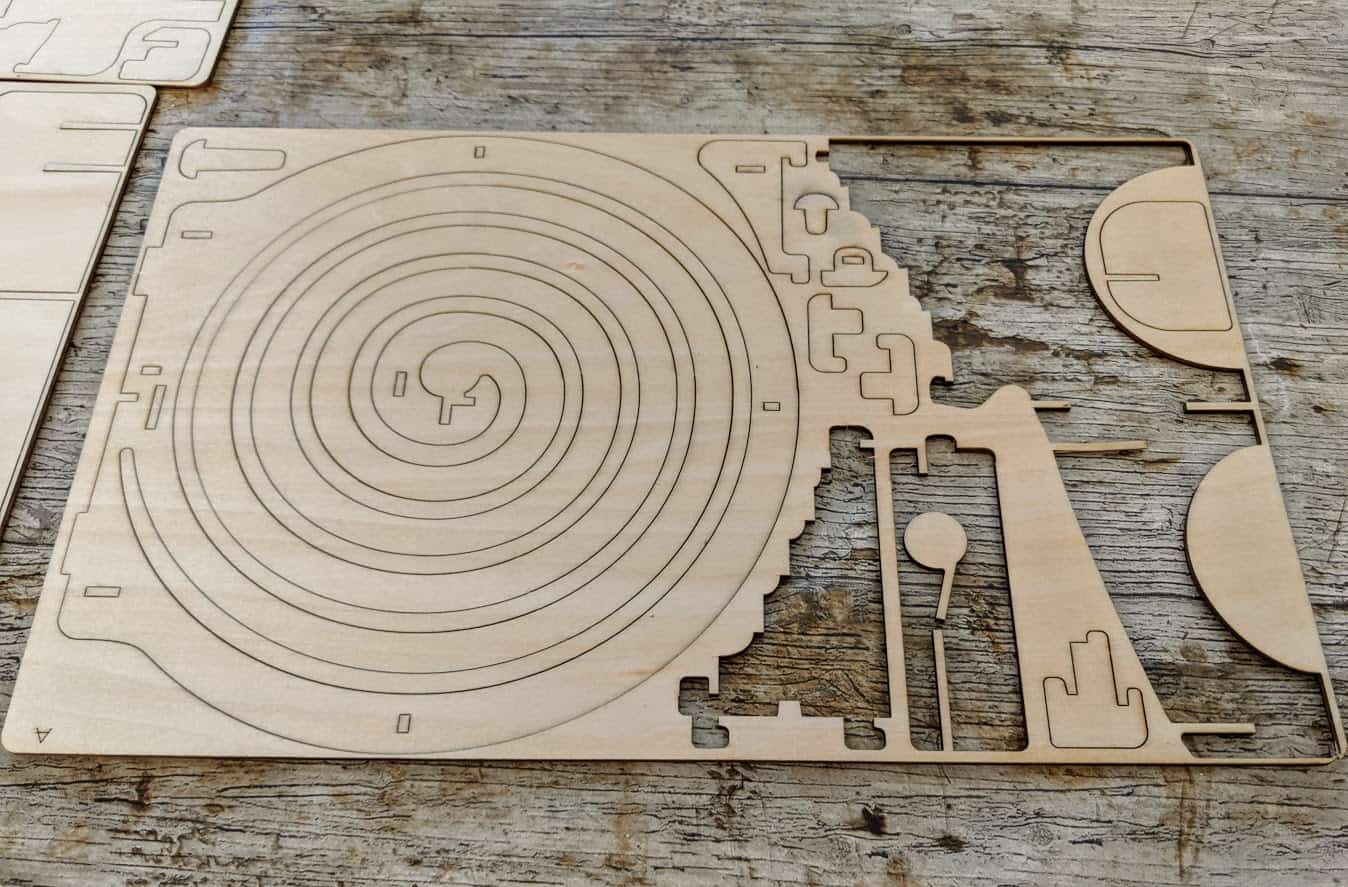 sheet of plywood with lazer cut shapes some of which have been removed to build the marble run.