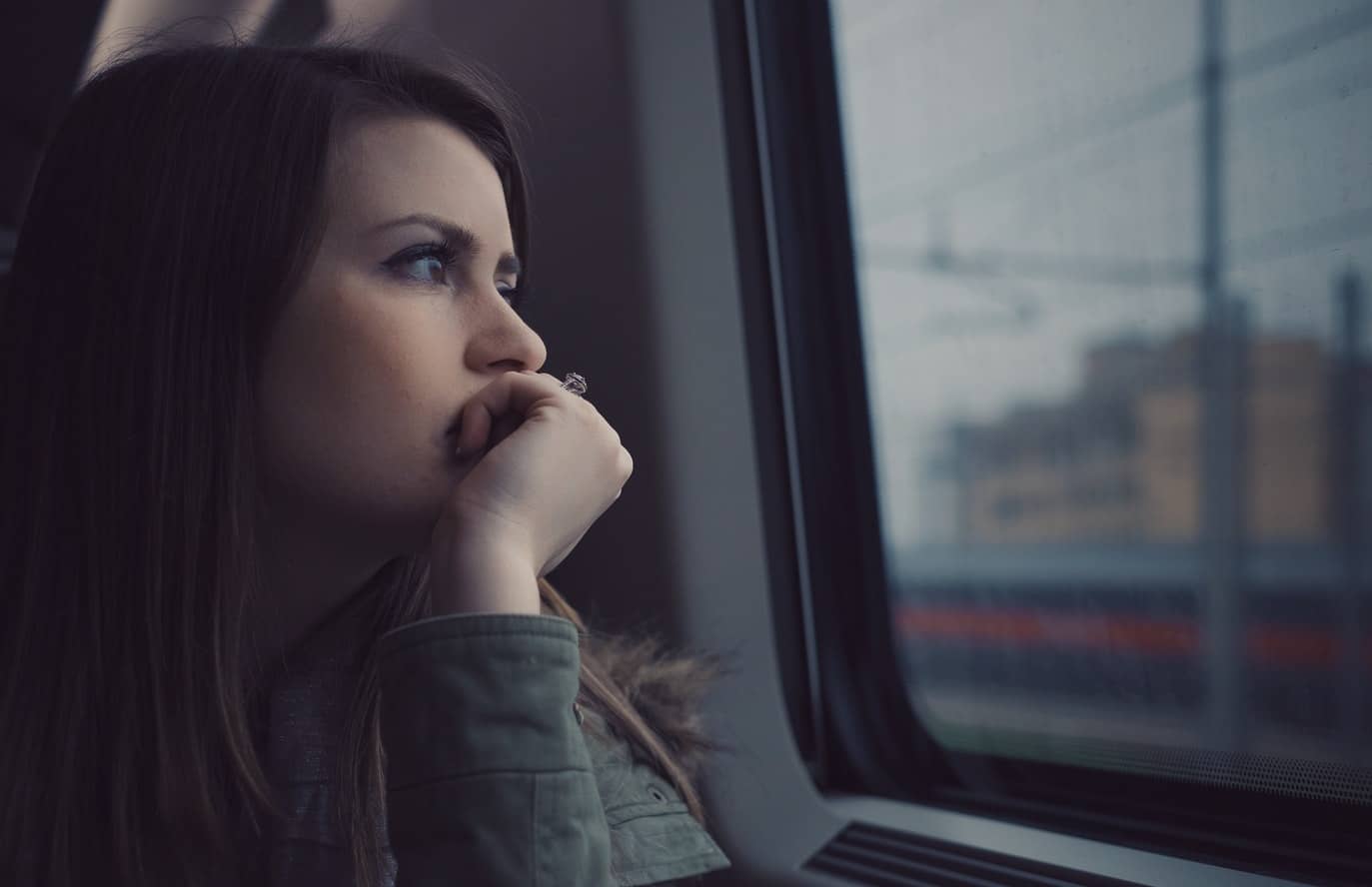Domestic abuse survivor staring out of a window thinking of her abuse