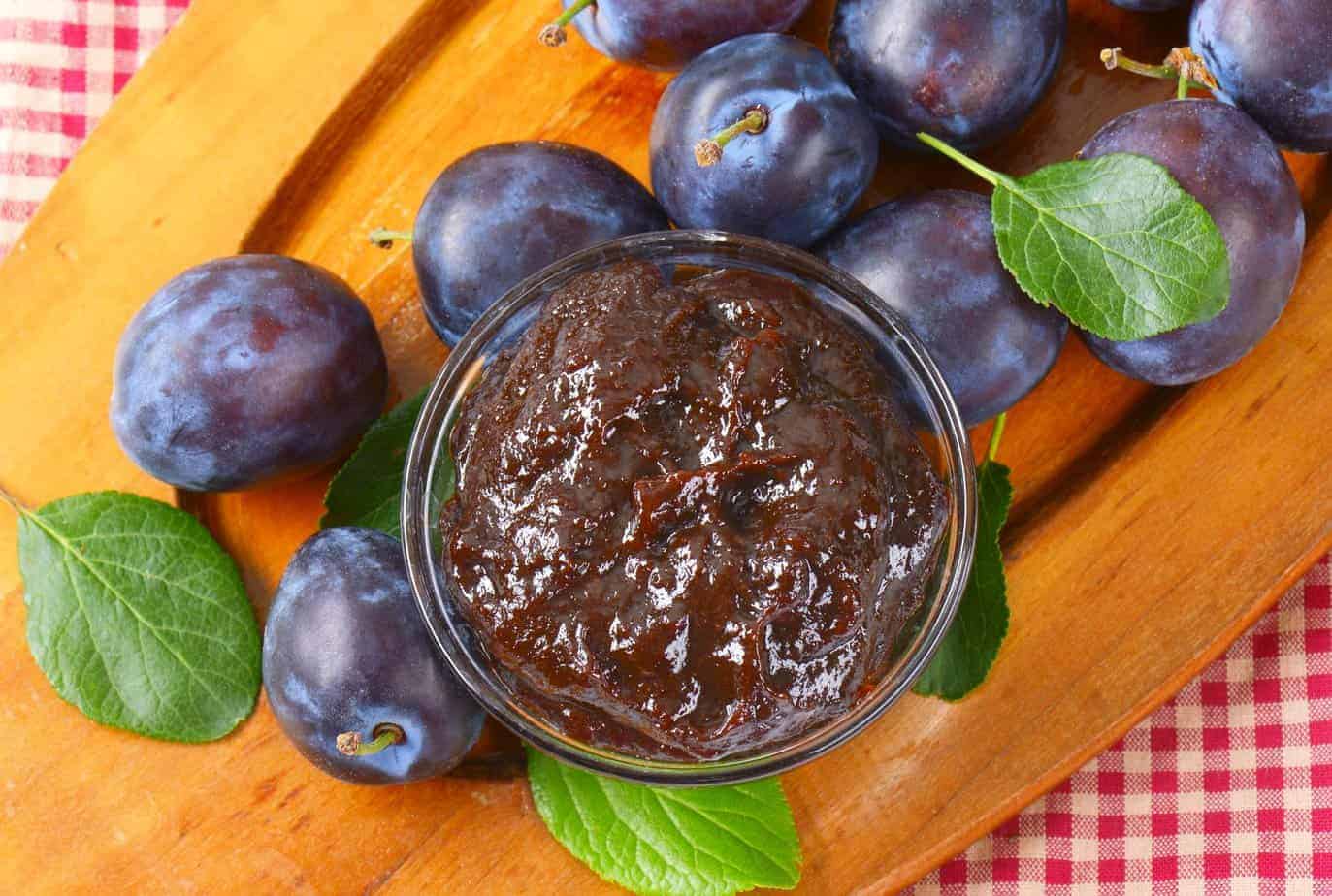 Powidlo Polish plum butter in a jar surrounded by plums.