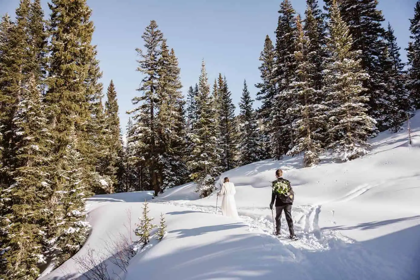 A couple snowshoeing in their wedding attire
