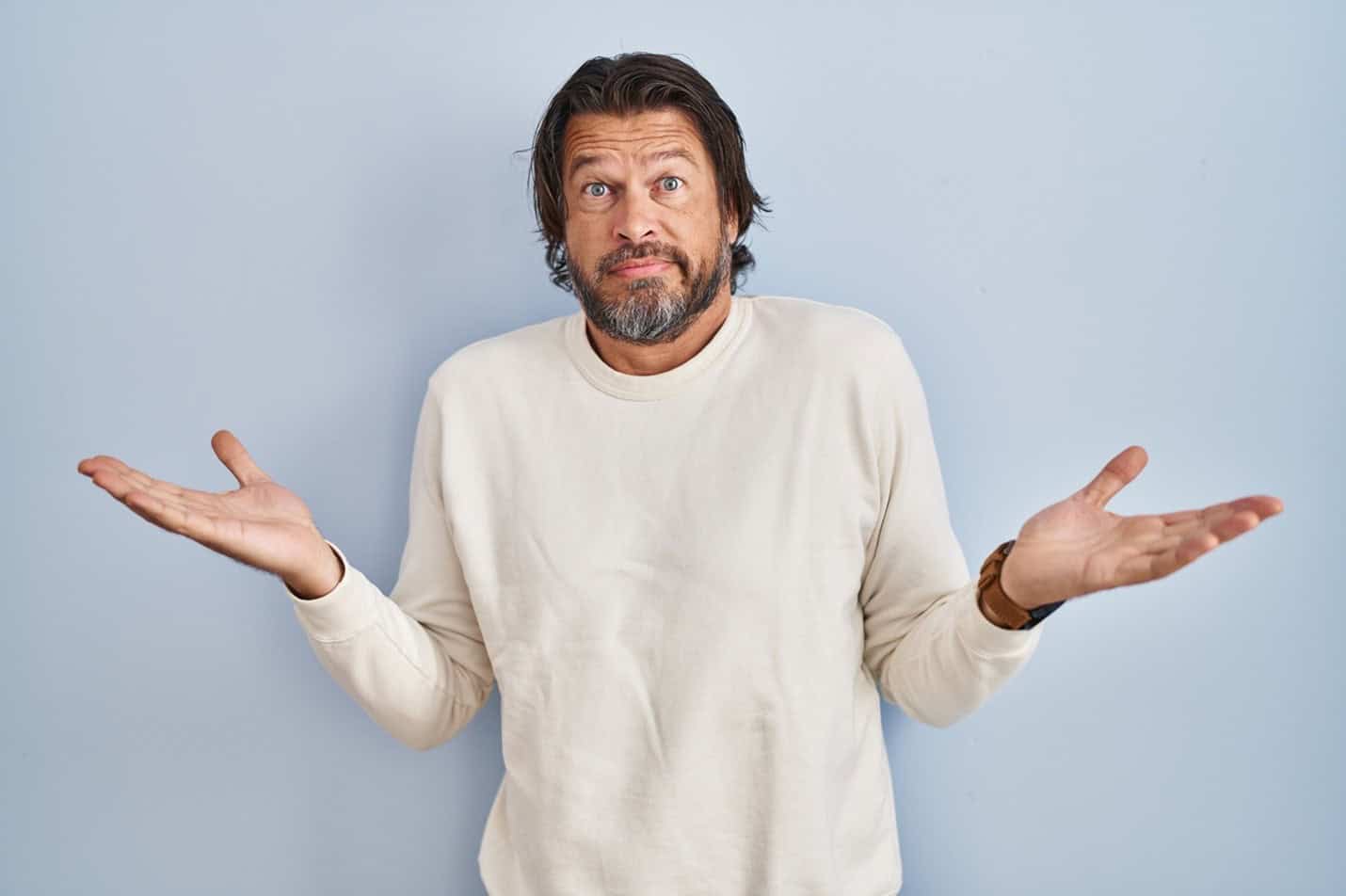 Confused man with hands raised quizzically and wondering what do most women want in a relationship.