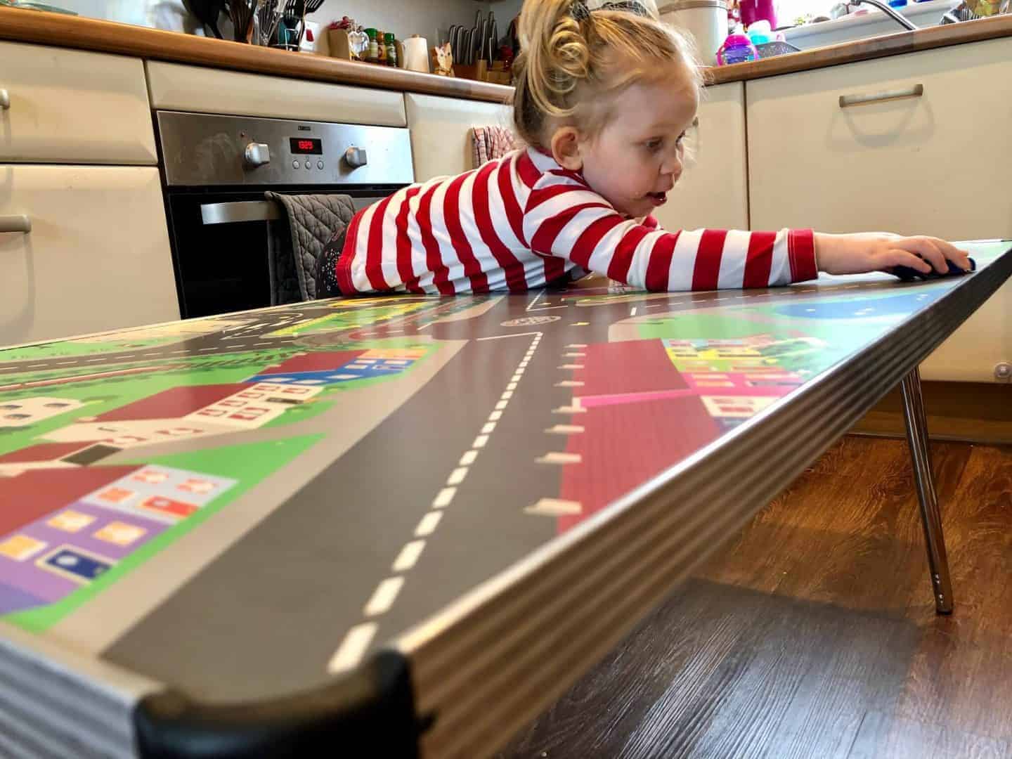 3 year old leaning over children's activity table