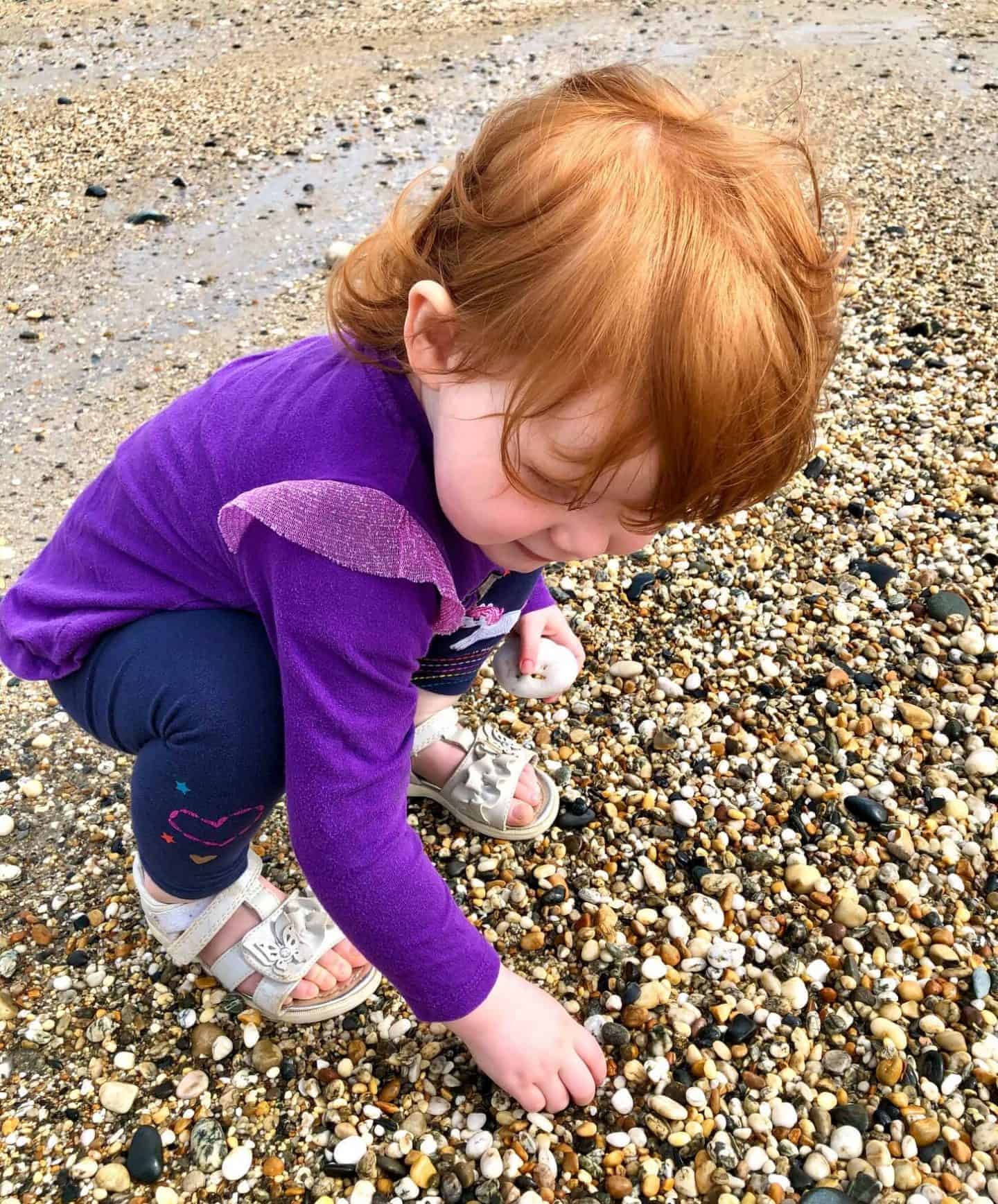 Little Dottie picking up pebbles at Marazion