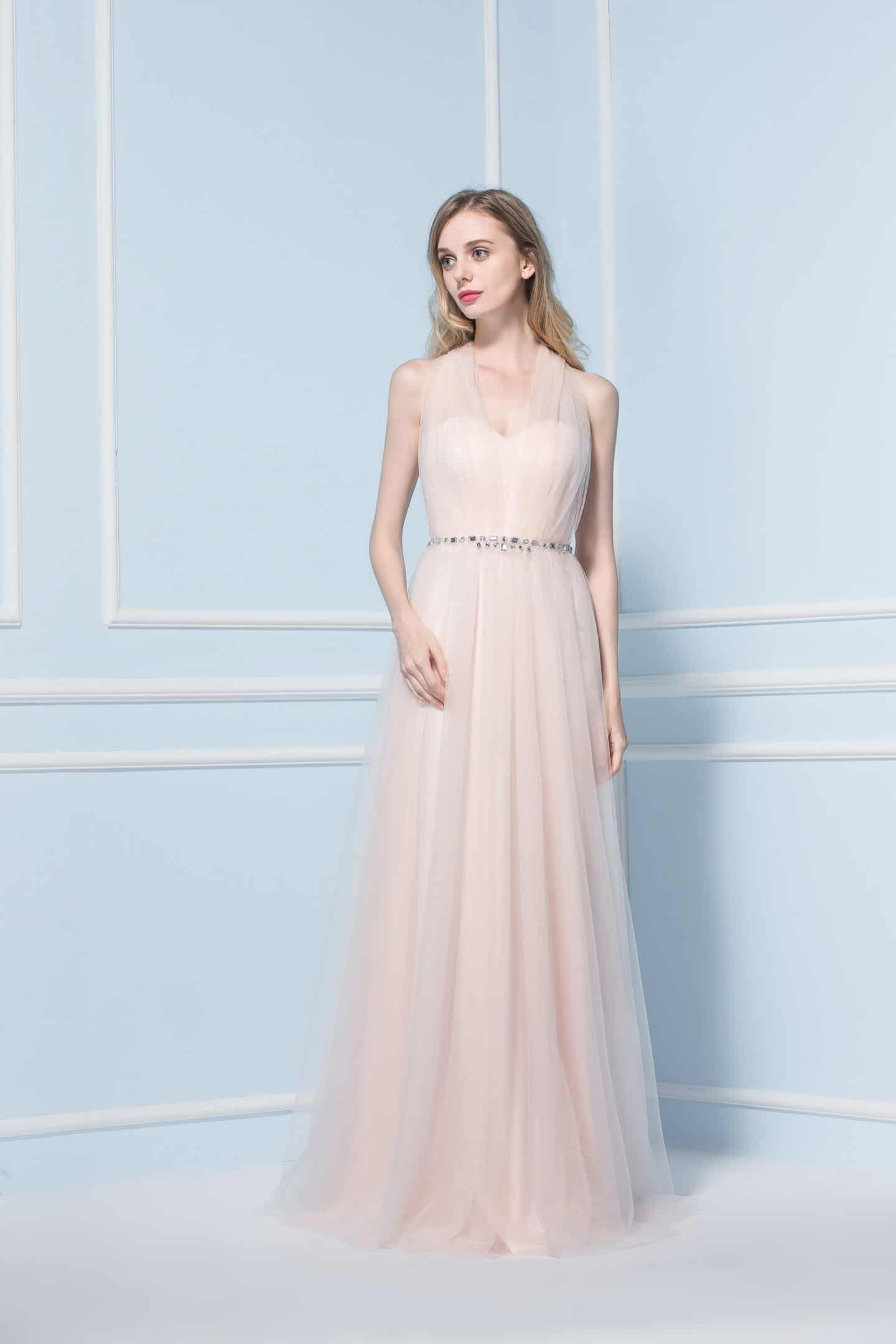 Woman wearing long pink dress in front of a blue wall