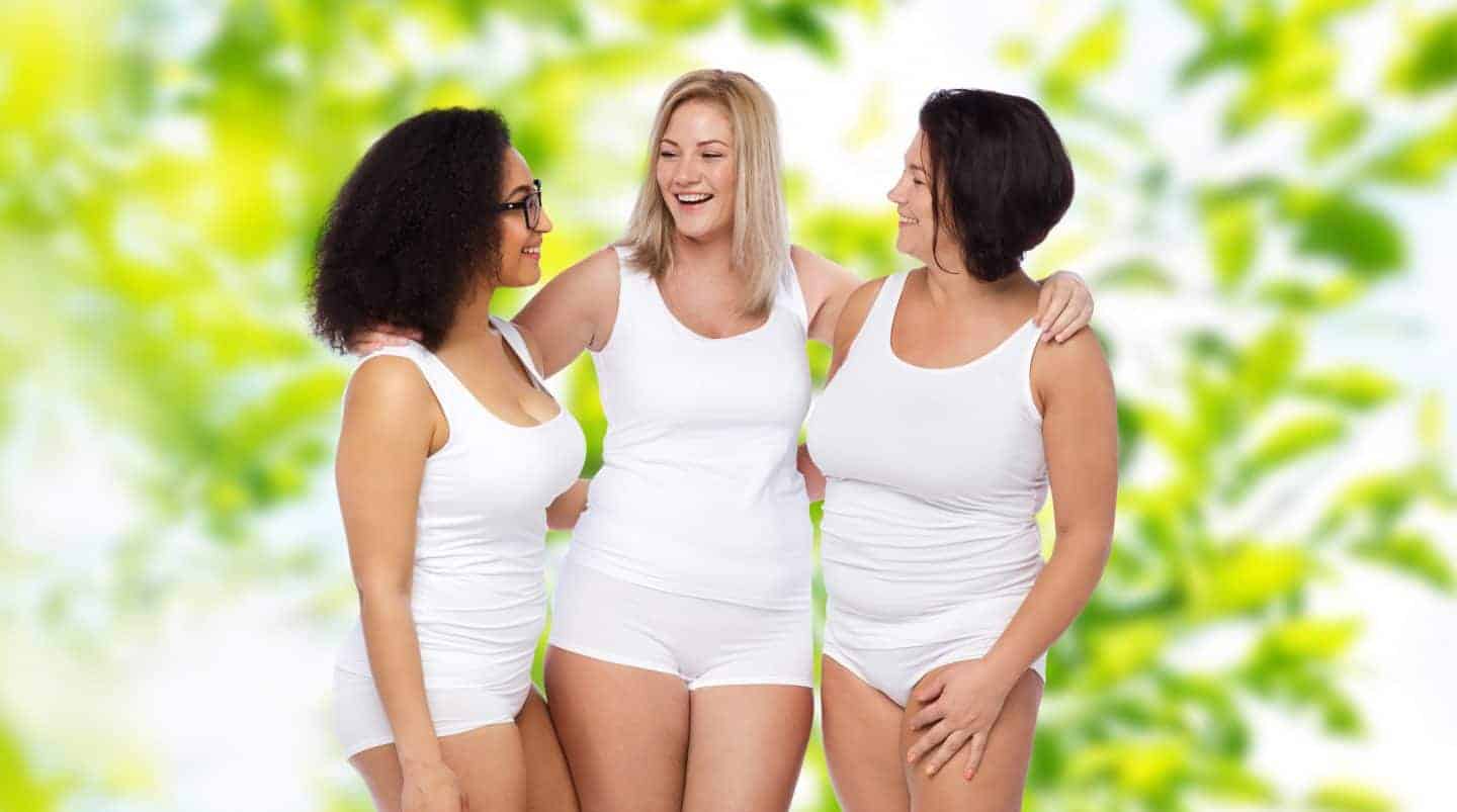Three women in white knickers and vests smiling and talking together