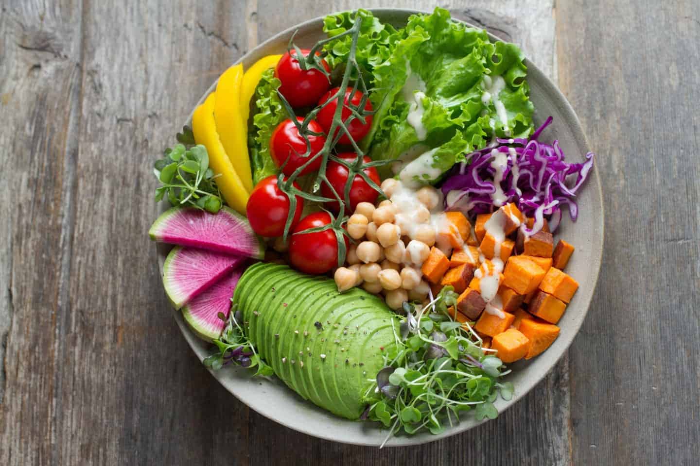 A bowl of saladsitting on top of a wooden table