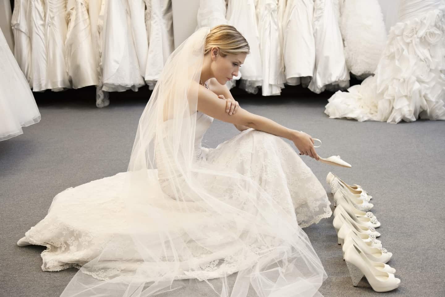 Blonde woman in wedding dress looking at white shoes