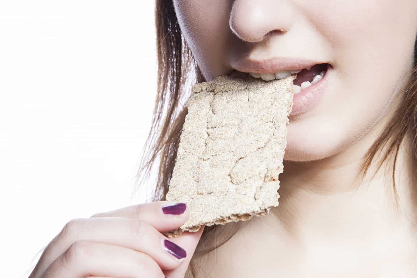 Detail shot of woman eating crispbread over white background