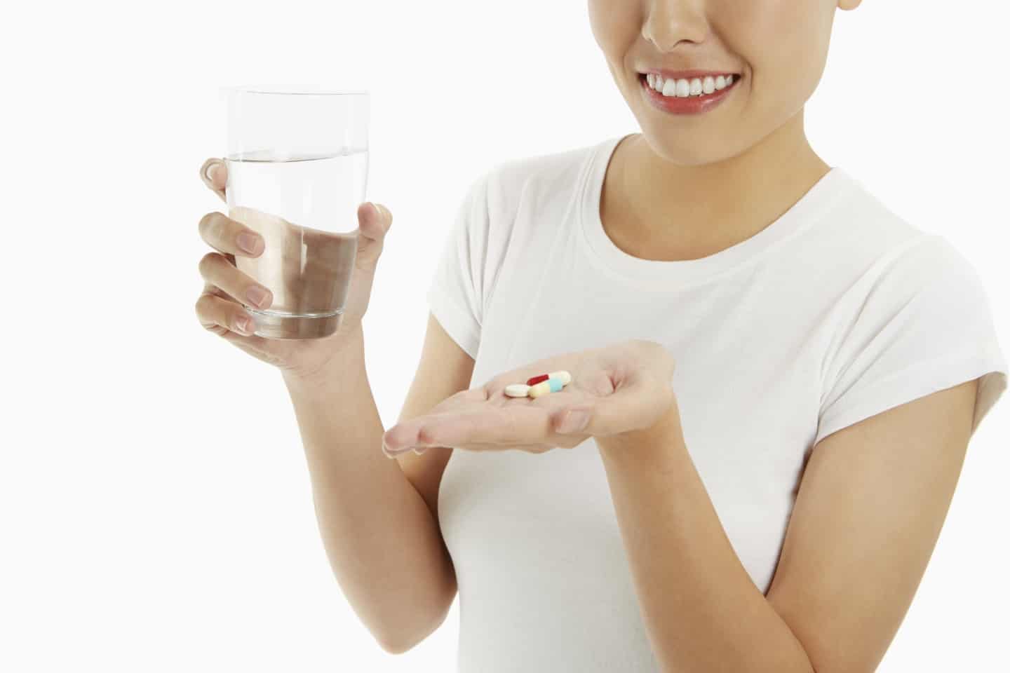 Woman with a glass of water and pills