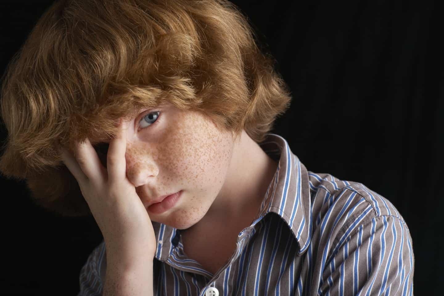 unwell boy with his hands on his face.