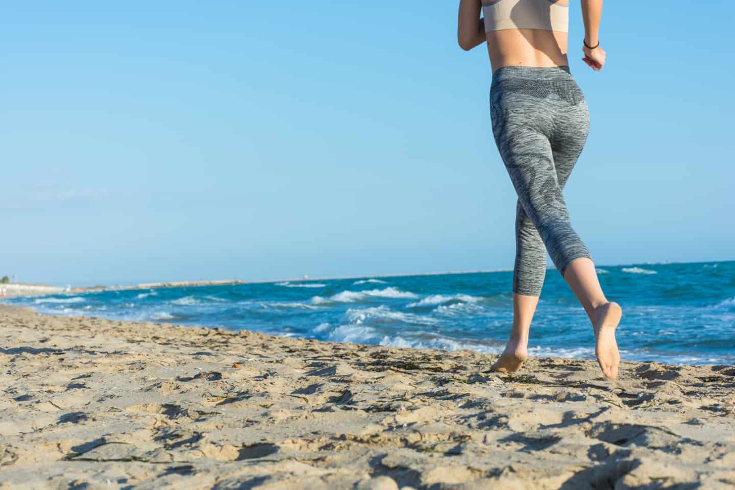 girl runs on beach at sunset. Barefoot. It keeps fit and tanning on vacation.