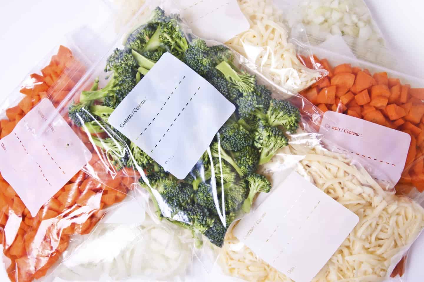 Chopped broccoli, carrots, onions and cheese in plastic freezer bags.