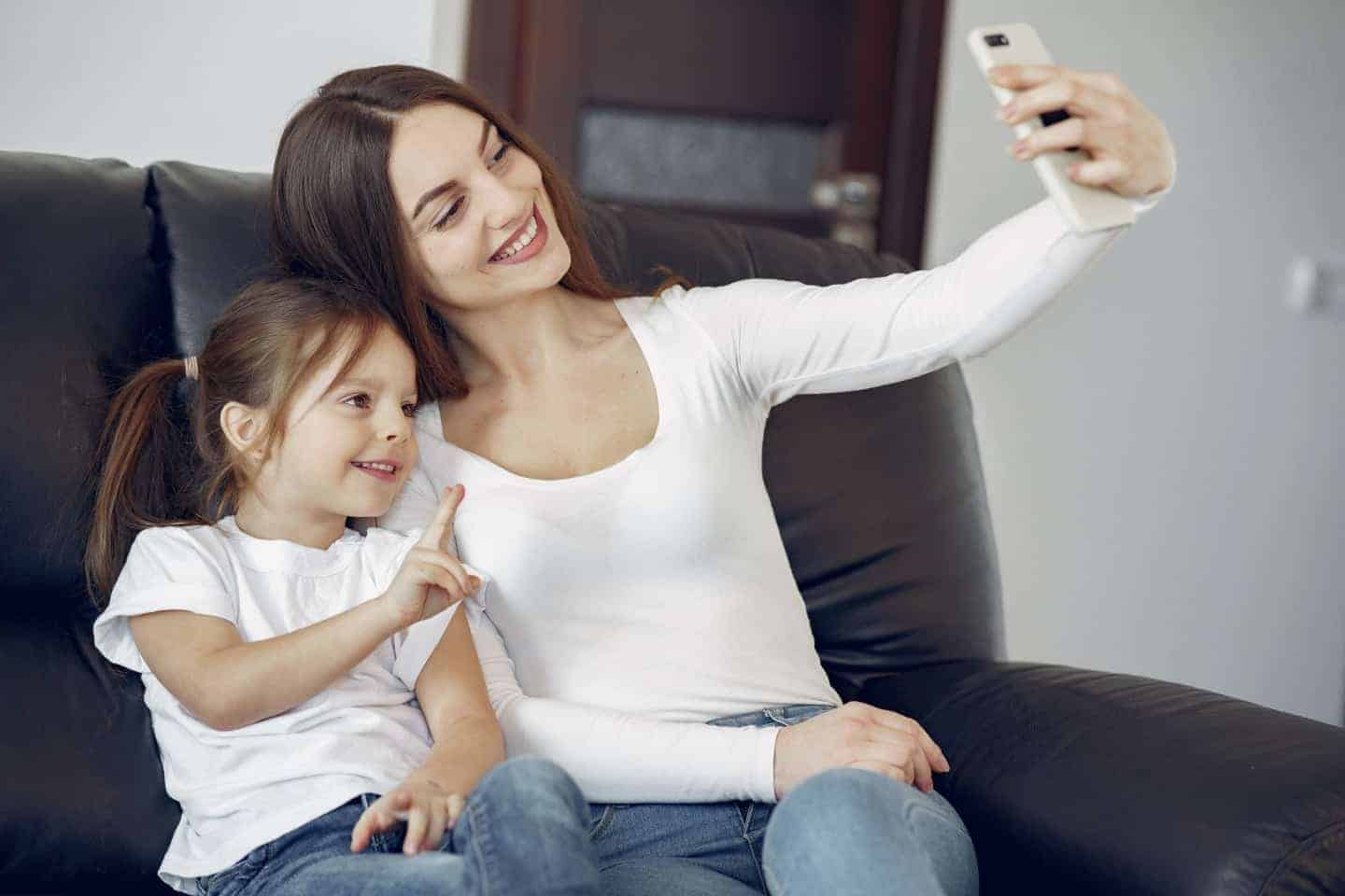 Woman and girl smiling at a camera taking a selfie