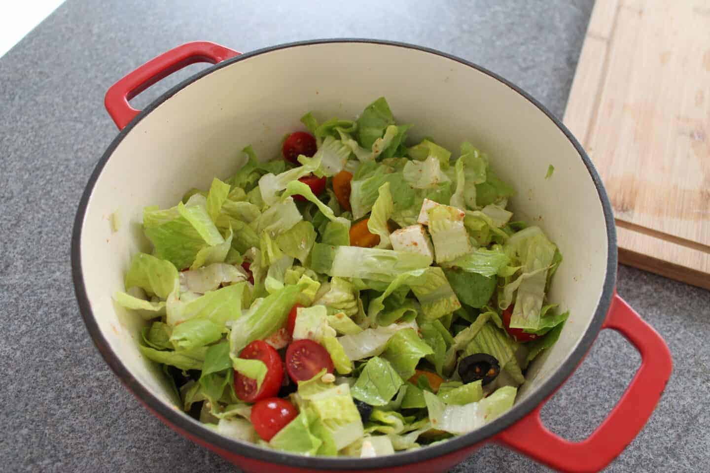 The salad ingredients all mixed up in the pan