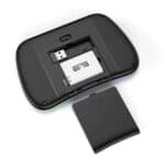 Battery compartment of a digital camera or electronic device with a removable battery, close-up shot with open back cover showing battery slot and SD card reader, black and white tones.