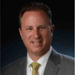 Professional man in a suit with a blurred face, representing leadership in university conference management and operational efficiency at CU Boulder using Kinetic Software.
