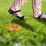 Woman wearing spiked lawn revitalizing aerating shoes