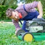 One guy portrait cutting the garden grass having problem with the lawn mower
