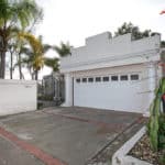 White Mission-style home with a stepped parapet roofline, a two-car garage with decorative columns, and drought-tolerant landscaping at 2823 Vancouver Ave in North Park.