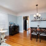 Open living and dining area at 3764 Alabama in North Park featuring hardwood floors, light blue walls, a wood dining table with cross-back chairs, and a dark wood sideboard.