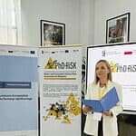 Uczestniczka PHD RISK Summer School prezentuje materiały podczas wydarzenia w sali konferencyjnej, z bannerami i ekranami w tle.