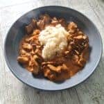 beef stroganoff with white rice in a grey bowl on a grey table