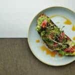 Smashed avocado meal on a white plate perfect for a meal with healthy fats.