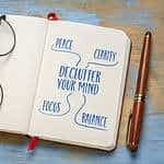 Declutter your mind for clarity, peace, focus and balance - handwriting in a notebook or journal with acup of tea, minimalism, self care and personal development concept.