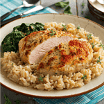 An image of chicken breast with rice and spinach on a beige plate