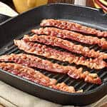An image of cooked bacon strips on a cast iron pan