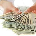 Am image of person's hands holding lots of american dollars