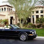 An image of expensive black car on the background of a huge house