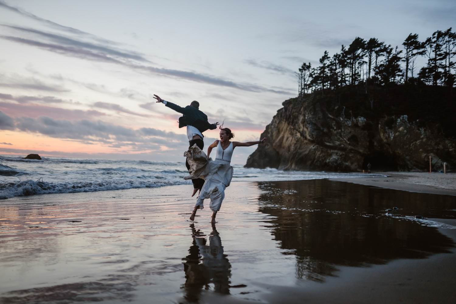Bride and Groom jumping in the air at Hug Point & Cannon Beach Elopement